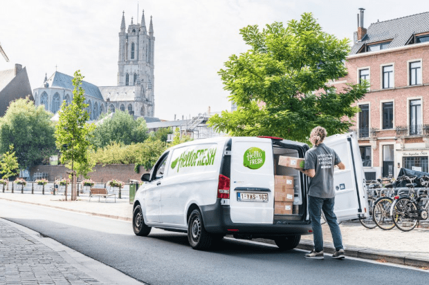 Screenshot 2025-03-28 at 4.23.17 PM Livraison d’une box HelloFresh par camionnette dans une ville européenne, avec un livreur en train de décharger les colis