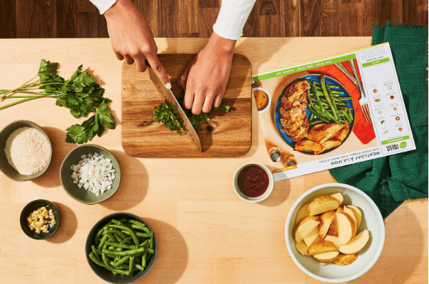 Screenshot 2025-04-07 at 7.14.22 PM Préparation d’un repas HelloFresh avec ingrédients frais sur un plan de travail : haricots verts, pommes de terre, persil et fiche recette visible.