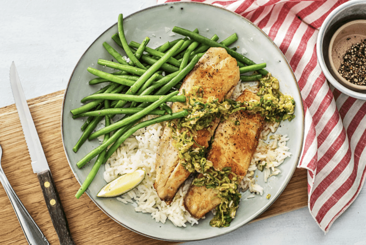 Screenshot 2025-04-11 at 1.05.13 PM Filet de poisson doré servi sur du riz basmati avec haricots verts vapeur et zestes de citron, assaisonné d'une sauce aux herbes