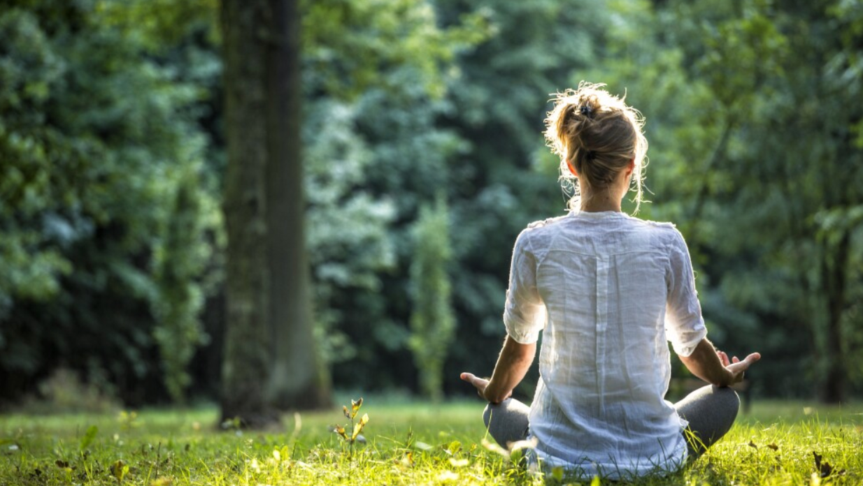 Screenshot 2025-06-28 at 11.43.11 AM Femme en méditation assise dans l’herbe, au cœur d’une forêt paisible et ensoleillée