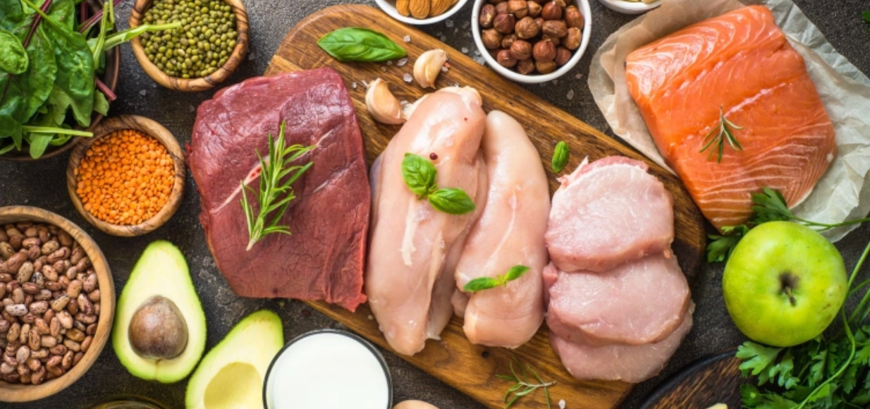 Assortiment d’aliments riches en protéines : viande rouge, filets de poulet, saumon, légumineuses, avocat, noix, lait et légumes frais