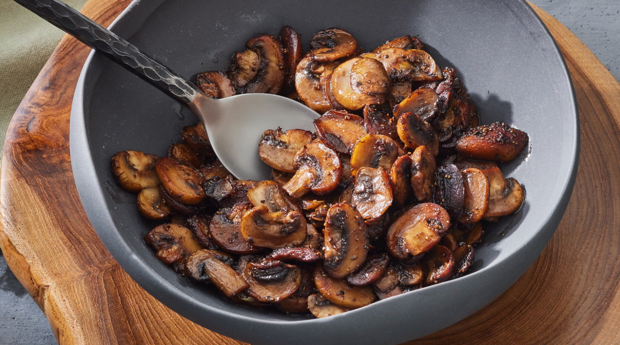 Bol de champignons sautés assaisonnés, servis avec une cuillère